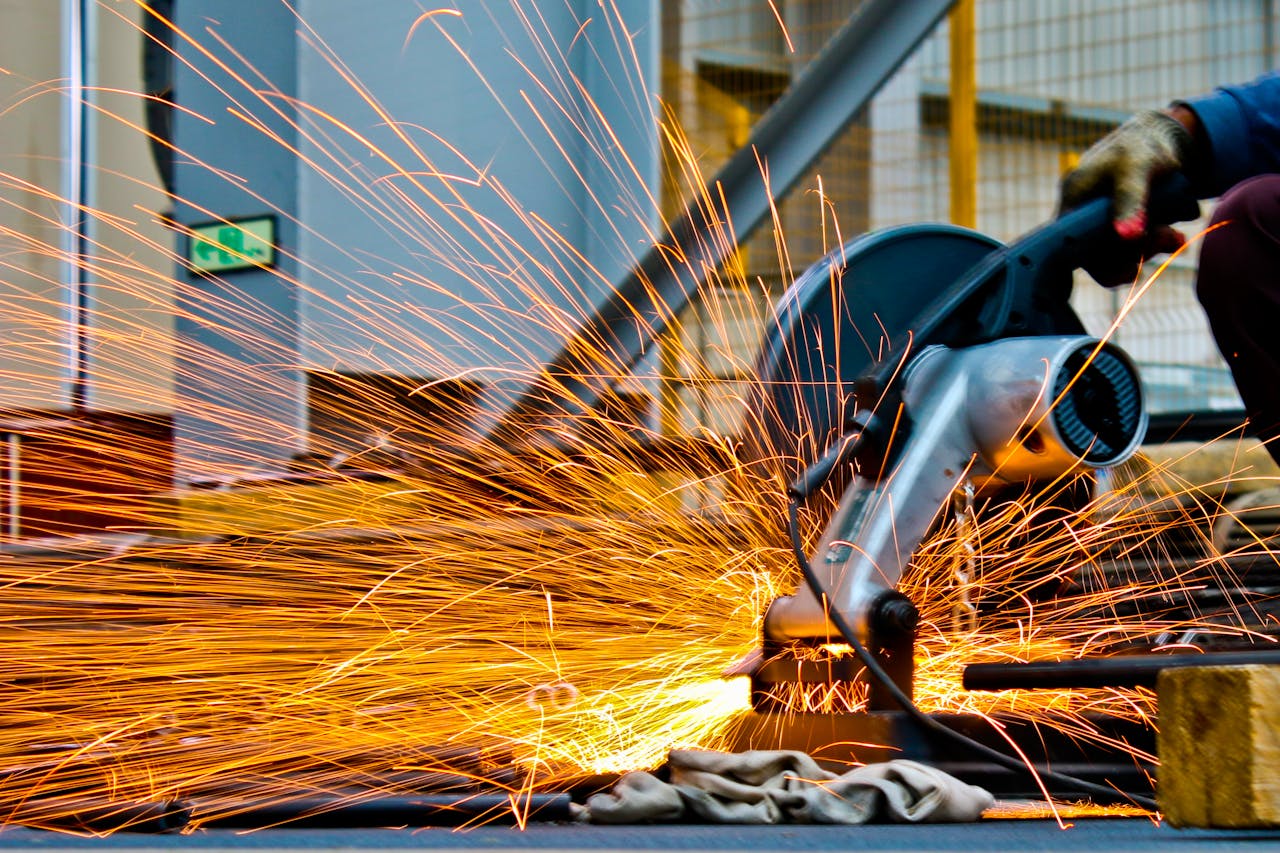 services-04 A worker operates a grinder cutting metal, creating a vibrant display of sparks in an industrial setting.