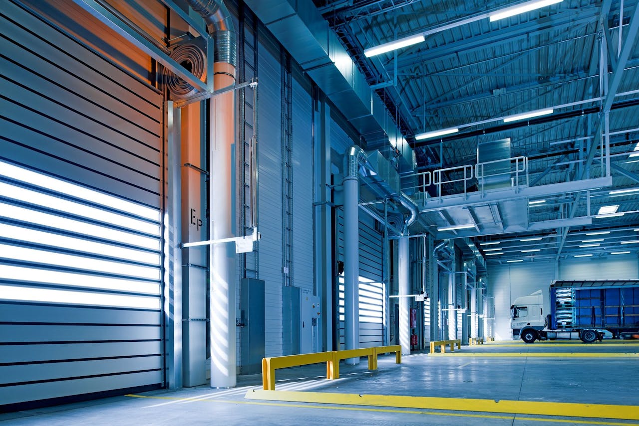 about-img Spacious and modern warehouse interior with parked truck and steel structures.